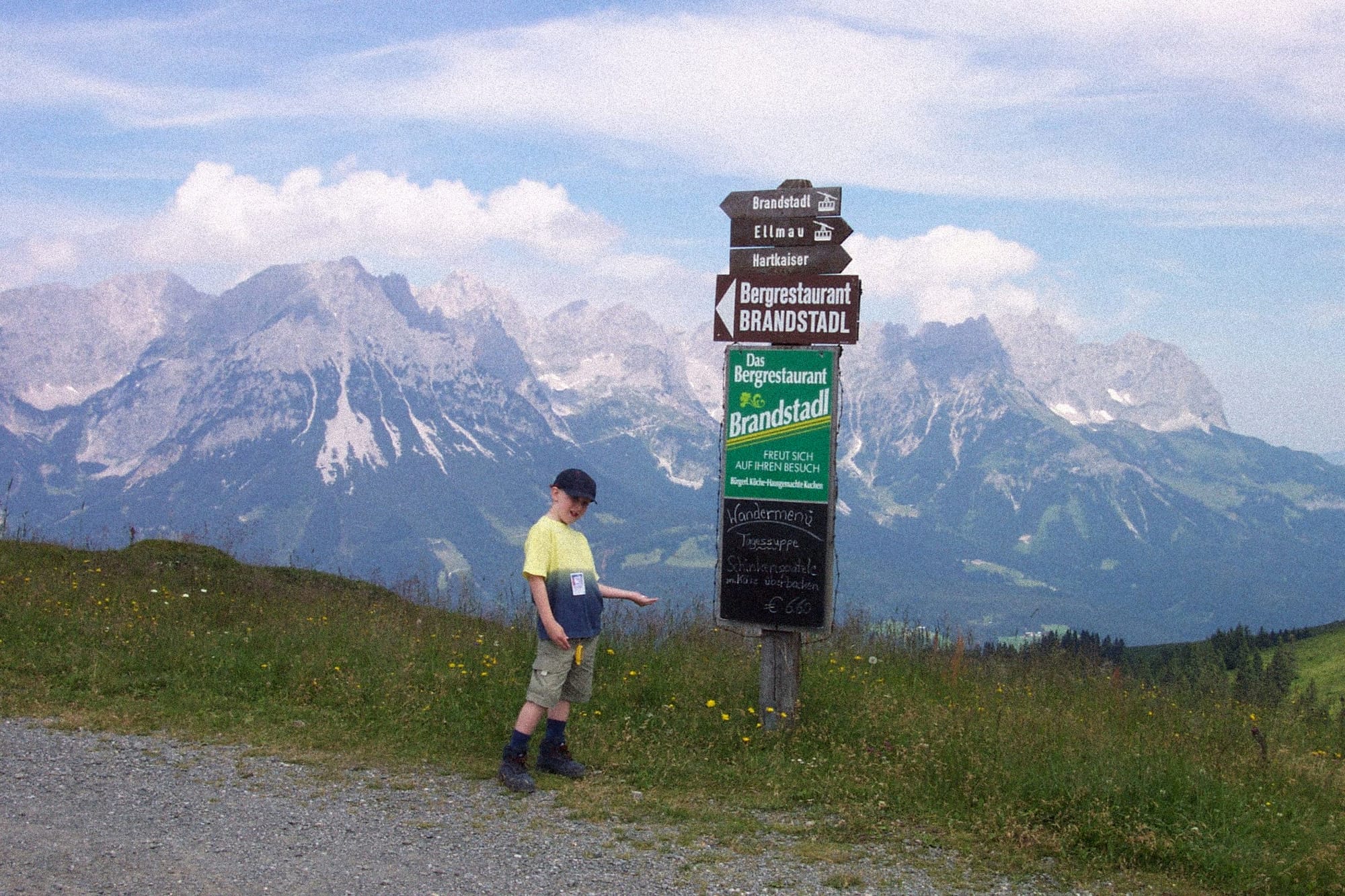 A young version of the author, standing in front of a sign while on a trail in the Austrian Alps